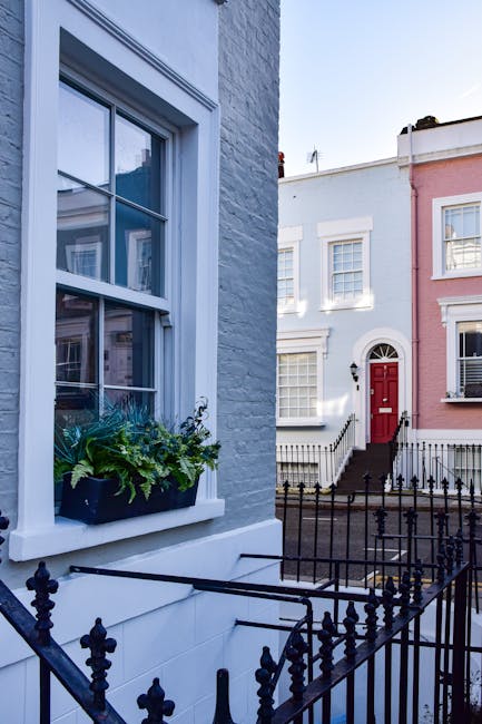 A two-story brick building on a cobblestone street housing Notting Hill Garage, a garden maintenance and landscaping service in Notting Hill. The building has a dark green facade with a large window a